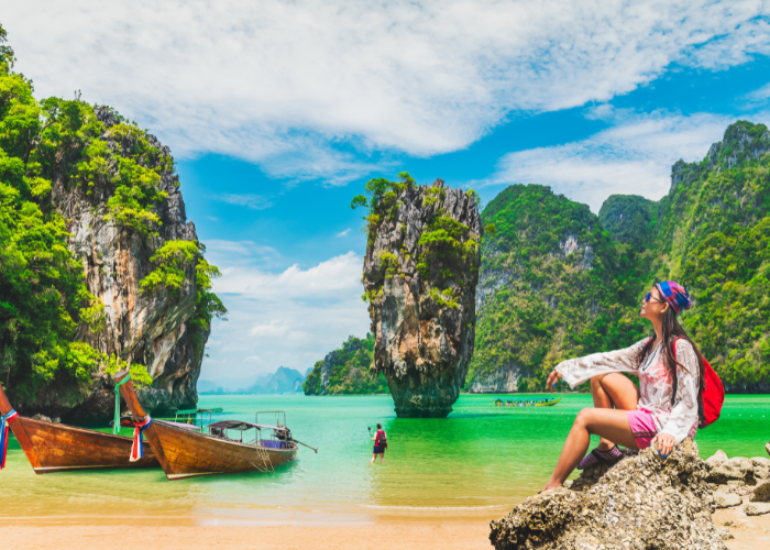 Traveller beside long-tail boats and limestone islands in Thailand